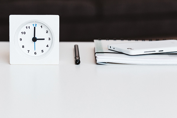 Schreibtisch mit Uhr, Stift, Block und Smartphone